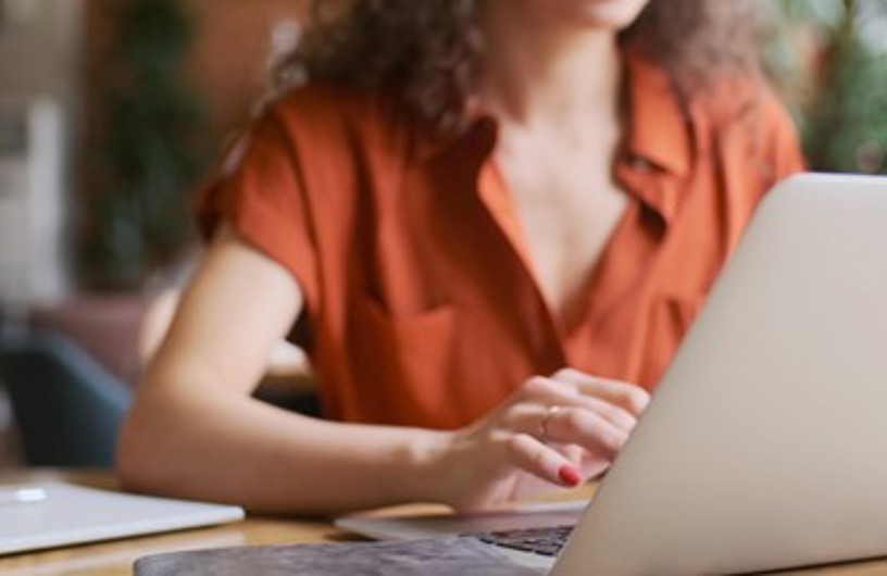 Antydningen af en kvinde, der sidder på en Macbook og skriver